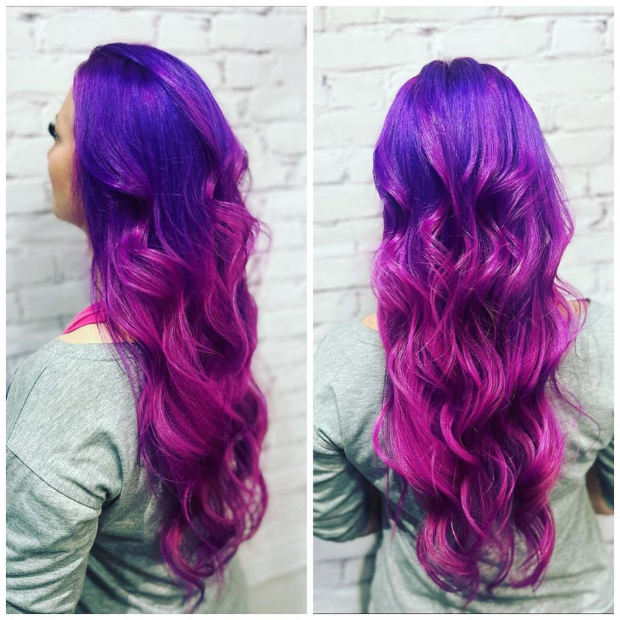 Long beach-wavy hair dyed in a vivid vibrant violet purple transitioning into a deep magenta pink ombre, styled at Silhouette Spa hair salon.