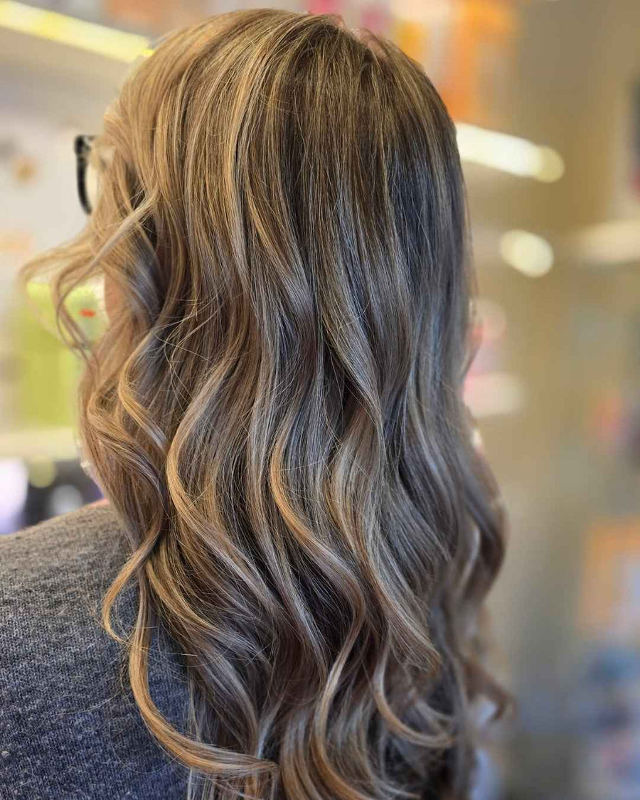 back profile of long brunette hair with warm honey blonde balayage highlights styled in loose beach waves at silhouette spa