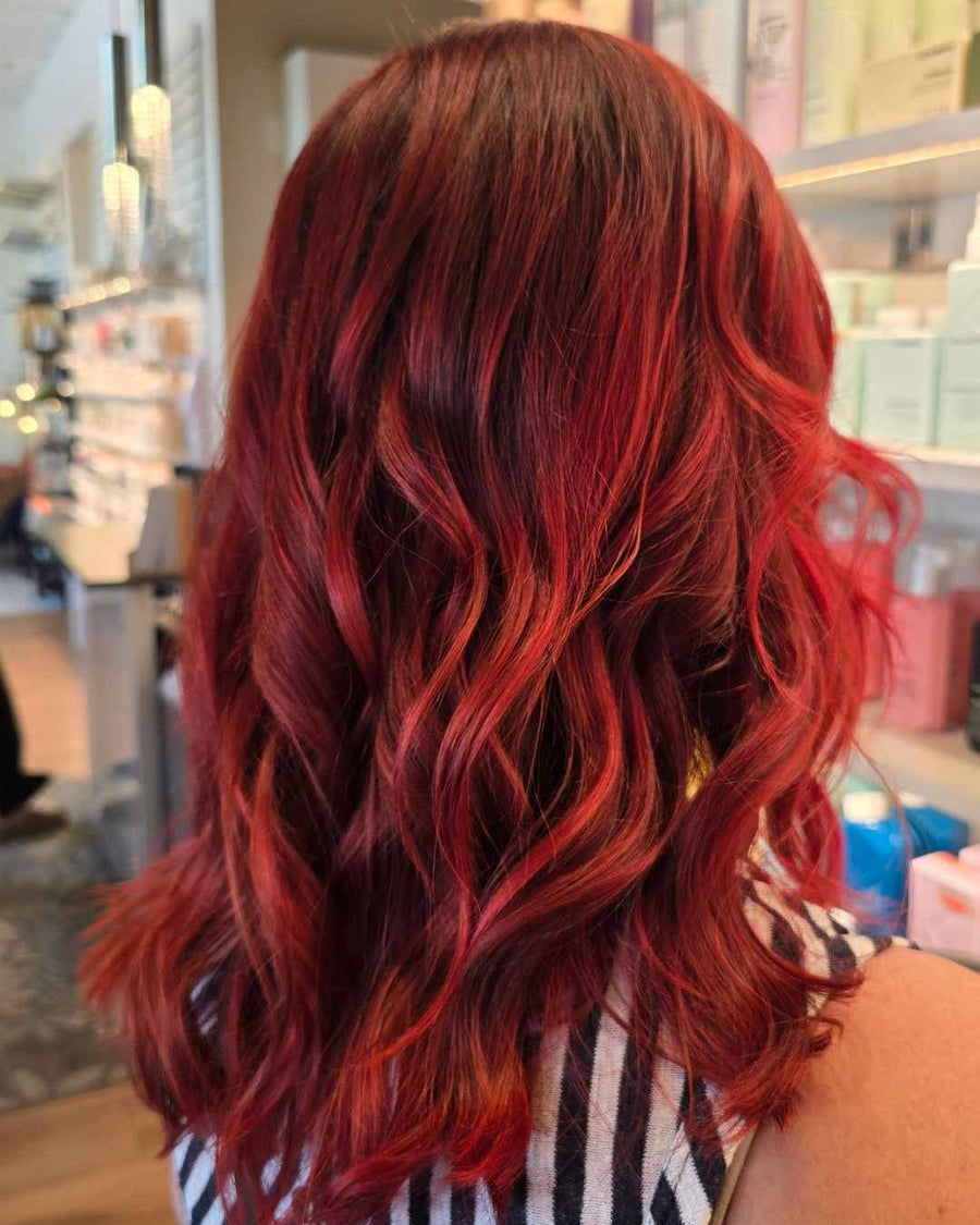 back view of medium length wavy hair dyed in a vibrant cherry red and crimson color treatment at silhouette spa hair salon